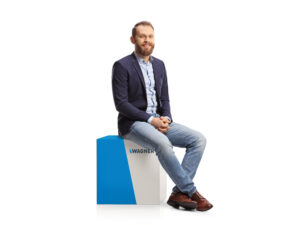 Young professional man sitting on a white cube and smiling 10